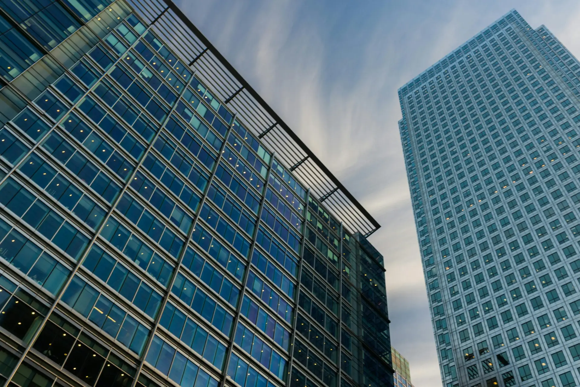 Upward perspective of modern glass skyscrapers with a blue sky background.